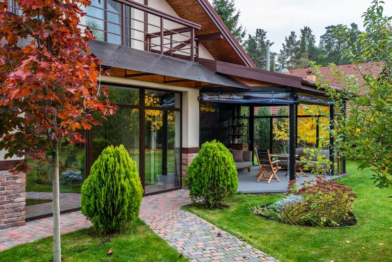 Haus mit verglastem Wintergarten und gepflegtem Garten